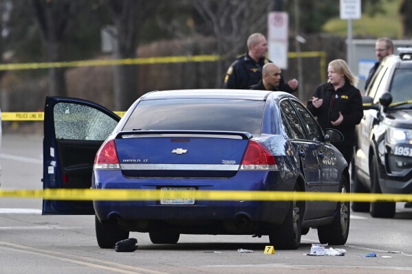 Investigators examine a car with a broken door window at the scene where a St. Paul police officer wounded in the leg in an exchange of gunfire with a suspect at the intersection of Cretin and Marshall Ave. in St. Paul, Minn. on Thursday, Dec. 7, 2023. (John Autey/Pioneer Press via AP)