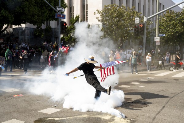 A demonstrator kicks a canister of tear gas during a protest Saturday, June 14, 2025, in Los Angeles. (AP Photo/Noah Berger)