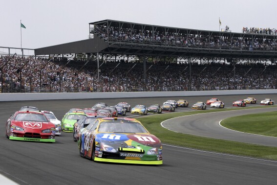 FILE - Elliott Sadler leads the field through the first turn on the start of the NASCAR Allstate 400 at the Brickyard at Indianapolis Motor Speedway in Indianapolis, Sunday, Aug. 7, 2005. NASCAR will return to the oval at Indianapolis Motor Speedway next season for the 30-year anniversary of stock cars racing at the historic venue. (AP Photo/Darron Cummings, File)