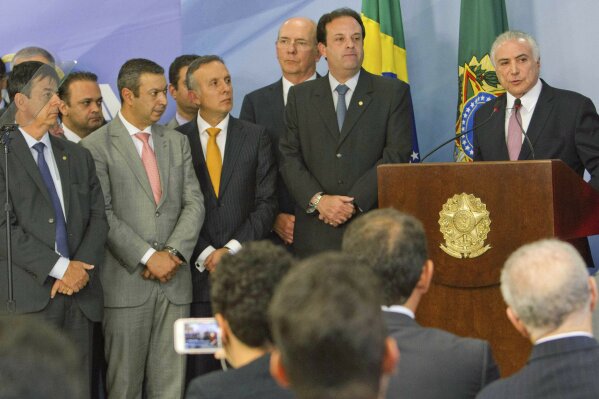 
              Brazil's President Michel Temer, right, speak during a statement accompanied by supporters and ministers of his government, at the Planalto Presidential Palace, in Brasilia, Tuesday, June 27, 2017. Temer has dismissed corruption allegations against him as a "soap opera plot" and cast doubt on the motivations of the country's top prosecutor a day after he presented a scathing indictment. (AP Photo/Eraldo Peres)
            