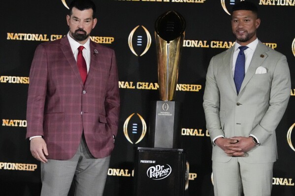 Ohio State head coach Ryan Day, left, and Notre Dame head coach Marcus Freeman pose with the trophy after a news conference ahead of the College Football Playoff national championship game Sunday, Jan. 19, 2025, in Atlanta. The game between Ohio State and Notre Dame will be played on Monday. (AP Photo/Chris Carlson)
