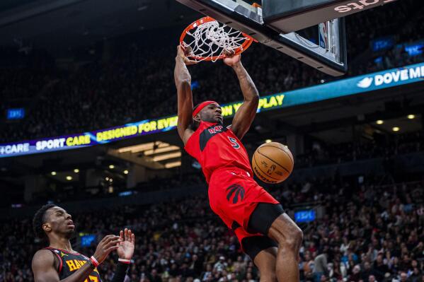 Toronto Raptors forward Precious Achiuwa hangs off the rim after dunking against the Atlanta Hawks during the first half of an NBA basketball game Saturday, Jan. 14, 2023, in Toronto. (Christopher Katsarov/The Canadian Press via AP)