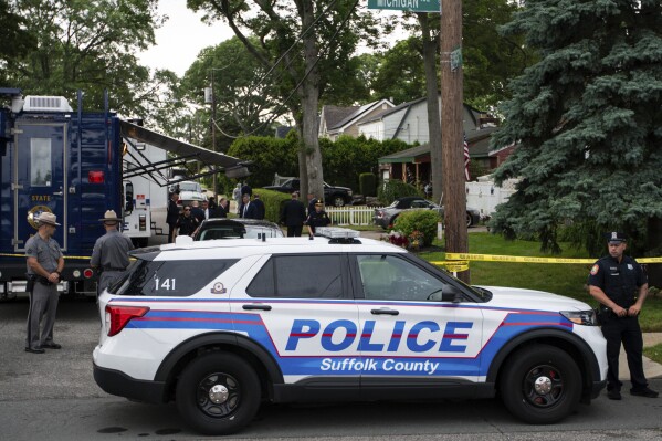 Police officers stand guard near the house where a suspect has been taken into custody on New York's Long Island in connection with a long-unsolved string of killings, known as the Gilgo Beach murders, Friday, July 14, 2023, in Massapequa Park, N.Y. (AP Photo/Eduardo Munoz Alvarez)