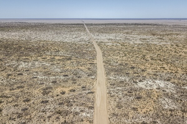 A dirt road stretches through the desert that used to be the bed of the Aral Sea, on the outskirts of Muynak, Uzbekistan, Tuesday, June 27, 2023. (AP Photo/Ebrahim Noroozi)