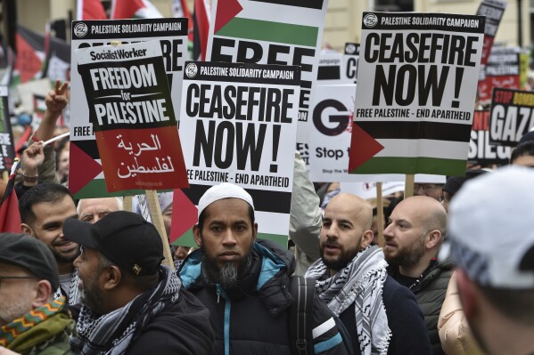 Pro-Palestinian protesters hold placards as they take part in a demonstration in London, Saturday, April 27, 2024. (AP Photo/Thomas Krych)