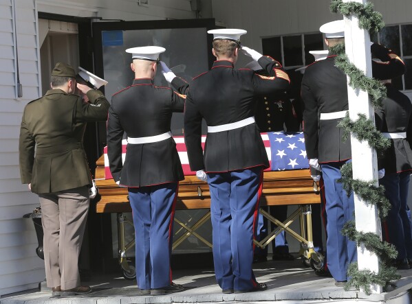 Marines salute the body of the late Marine Capt. Jack Casey, who died in a helicopter crash with four other Marines, at the Wiggin-Purdy-McCooey-Dion Funeral Home in Dover, N.H., on Tuesday, Feb. 20, 2024. Casey was one of the five Marines killed when their helicopter went down in the mountains outside San Diego during a storm. (Deb Cram/Foster's Daily Democrat via AP)