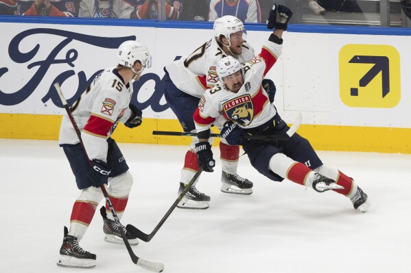 Florida Panthers' Brad Marchand (63) celebrates his game-winning goal against the Edmonton Oilers with Jesper Boqvist (70) and Anton Lundell (15) during the second overtime period in Game 2 of the NHL Stanley Cup final in Edmonton, Friday, June 6, 2025.(Jason Franson/The Canadian Press via AP)