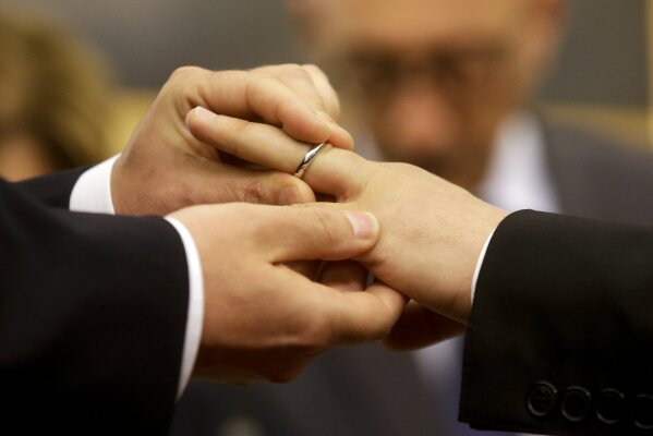 FILE - In this May 21, 2015 file photo, Mauro Cioffari, left, puts a wedding ring on his partner Davide Conti's finger as their civil union is being registered by a municipality officer during a ceremony in Rome's Campidoglio Capitol Hill. Pope Francis endorsed same-sex civil unions for the first time as pope while being interviewed for the feature-length documentary “Francesco,” which premiered Wednesday, Oct. 21 2020 at the Rome Film Festival. (AP Photo/Gregorio Borgia, file)