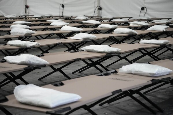 FILE - Bags containing a pillow, towel, and bed sheets are placed on cots inside the dormitory tent during a media tour of a shelter New York City is setting up to house up to 1,000 migrants in the Queens borough of New York, Tuesday, Aug. 15, 2023. About 3,000 asylum-seekers have been told their time was up in New York City shelters, but about half have reapplied to stay, according to a newspaper report, Friday, Oct. 20, 2023. (AP Photo/Mary Altaffer, File)