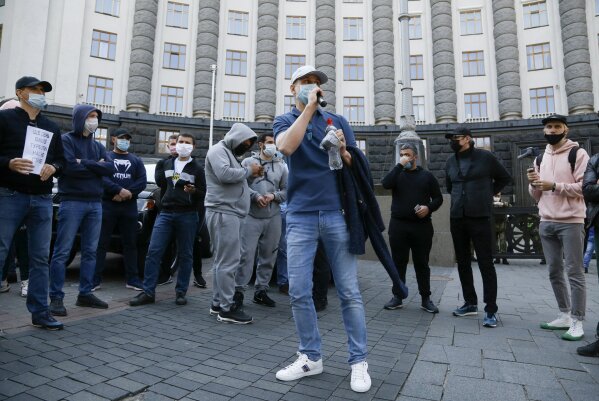 Workers of small business wearing face masks to protect from coronavirus demand the government to stop the quarantine, during a protest action in front of the Cabinet in Kyiv, Ukraine, Wednesday, April 29, 2020. The businessmen claim they are loosing their jobs because of the COVID-19 quarantine which was introduced in the country on March 12. (AP Photo/Efrem Lukatsky)