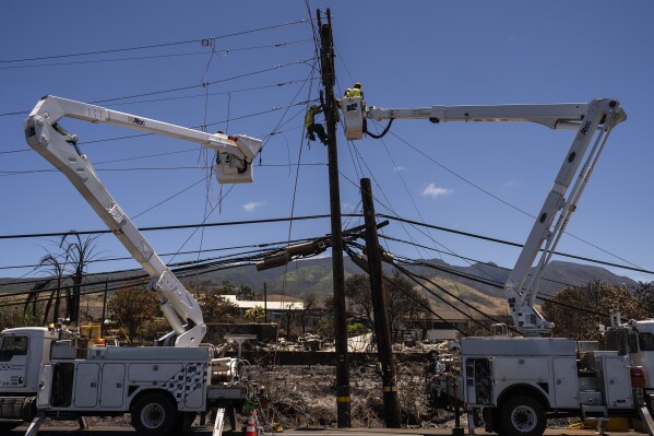 FILE - Electric crews work on power lines in the aftermath of a devastating wildfire in Lahaina, Hawaii, Thursday, Aug. 17, 2023. Lawyers for Lahaina residents and business owners told a court Tuesday, Sept. 5, that cable TV and telephone companies share in responsibility for the wildfires that devastated the island. (AP Photo/Jae C. Hong, File)