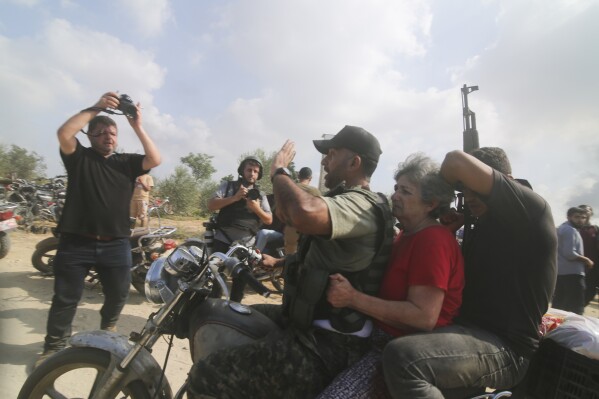 Palestinians transport a captured Israeli civilian, center, from Kibbutz Kfar Azza into the Gaza Strip on Saturday, Oct. 7, 2023. The militant Hamas rulers of the Gaza Strip carried out an unprecedented, multi-front attack on Israel at daybreak Saturday, firing thousands of rockets as dozens of Hamas fighters infiltrated the heavily fortified border in several locations by air, land, and sea and catching the country off-guard on a major holiday. (AP Photo)