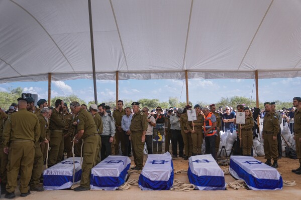 Mourners gather around the five coffins of the Kotz family during their funeral in Gan Yavne, Israel, Tuesday, Oct. 17, 2023. The family was killed by Hamas militants on Oct. 7 at their house in Kibbutz Kfar Azza near the border with the Gaza Strip, More than 1,400 people were killed and some 200 captured in an unprecedented, multi-front attack by the militant group that rules Gaza. (AP Photo/Ohad Zwigenberg)