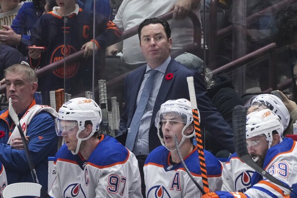 Edmonton Oilers head coach Jay Woodcroft, center, stands on the team bench during the third period of an NHL hockey game against the Vancouver Canucks, in Vancouver, British Columbia, on Nov. 6, 2023. Woodcroft is out as coach of the Oilers after the supposed Stanley Cup contenders lost 10 of their first 13 games this season. Woodcroft was fired Sunday, Nov. 12, 2023. Kris Knoblauch, Connor McDavid's junior hockey coach, was named Woodcroft's replacement, and Hall of Famer Paul Coffey joins his staff as an assistant. (Darryl Dyck/The Canadian Press via AP)