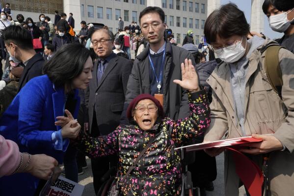 South Korean forced labor victim Yang Geum-deok, bottom center, reacts after a rally against the South Korean government's announcement of a plan over the issue of compensation for forced labors at the National Assembly in Seoul, South Korea, Tuesday, March 7, 2023. South Korean President Yoon Suk Yeol on Tuesday defended his government's contentious plan to use local funds to compensate Koreans enslaved by Japanese companies before the end of World War II, saying it's crucial for Seoul to build future-oriented ties with its former colonial overlord. (AP Photo/Ahn Young-joon)
