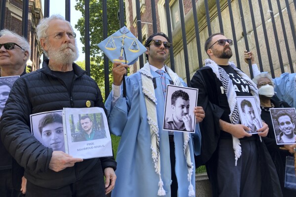 Mohsen Mahdawi, center, holds a photo of Mahmoud Khalil while posing for a photo with demonstrators outside the gates of Columbia University after graduating, Monday, May 19, 2025, in New York. (AP Photo/Jake Offenhartz)