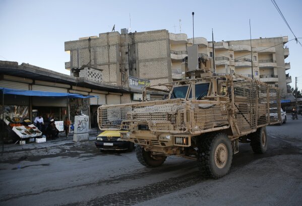 
              A vehicle of U.S. troops passes on a street, in Manbij town, north Syria, Saturday, March 31, 2018. President Donald Trump's unscripted public declaration this week about pulling out of Syria "very soon" while at odds with his own policy are unnerving for the Kurds in this context. U.S. troops first deployed in the area about 16 months ago, after Turkish-backed Syrian forces advanced on areas near Manbij, in a race for control of territories as IS militants collapsed. The deployment prevented repeated clashes between the two rival forces. (AP Photo/Hussein Malla)
            