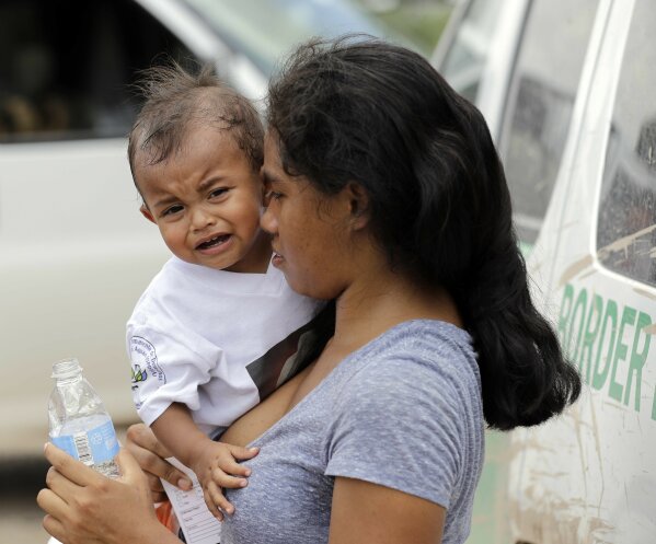 
              A mother migrating from Honduras holds her 1-year-old child as surrendering to U.S. Border Patrol agents after illegally crossing the border Monday, June 25, 2018, near McAllen, Texas. (AP Photo/David J. Phillip)
            