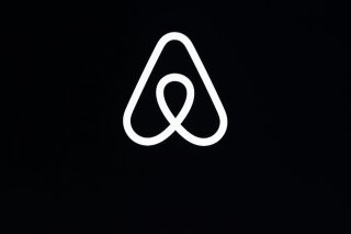 FILE - This Feb. 22, 2018, file photo, shows an Airbnb logo during an event in San Francisco. On Wednesday, Aug. 12, 2020, Airbnb announced that for the first time, it is taking legal action agains...