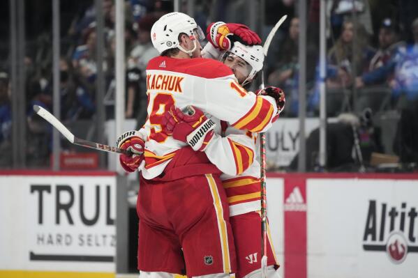 Calgary Flames left wing Matthew Tkachuk, left, congratuates left wing Johnny Gaudreau, who scored in overtime against the Colorado Avalanche in an NHL hockey game Saturday, March 5, 2022, in Denver. The Flames won 4-3. (AP Photo/David Zalubowski)