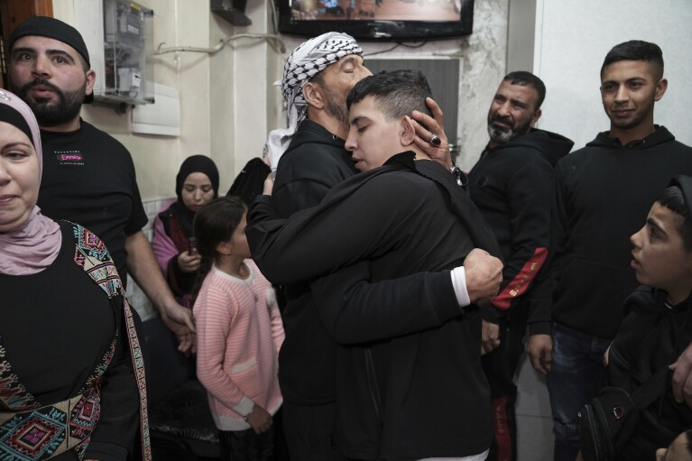 Ahmed Salaima, 14, center, a Palestinian prisoner released by Israel, is hugged by his father as he arrives home in the east Jerusalem neighborhood of Ras al-Amud, Tuesday, Nov. 28, 2023.  (AP Photo/Mahmoud Ilian)