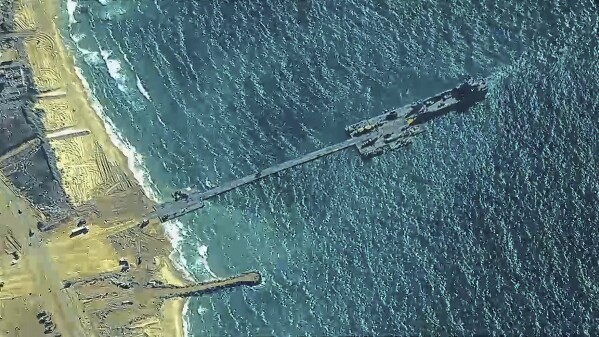 The image provided by U.S, Central Command, shows U.S. Army soldiers assigned to the 7th Transportation Brigade (Expeditionary), U.S. Navy sailors assigned to Amphibious Construction Battalion 1, and Israel Defense Forces placing the Trident Pier on the coast of Gaza Strip on Thursday, May 16, 2024. The temporary pier is part of the Joint Logistics Over-the-Shore capability. The U.S. military finished installing the floating pier on Thursday, with officials poised to begin ferrying badly needed humanitarian aid into the enclave besieged over seven months of intense fighting in the Israel-Hamas war. (U.S. Central Command via AP)