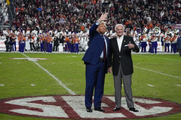 FILE - Republican presidential candidate and former President Donald Trump waves with South Carolina Gov. Henry McMaster during halftime in an NCAA college football game between the University of South Carolina and Clemson Saturday, Nov. 25, 2023, in Columbia, S.C. (AP Photo/Chris Carlson, File)