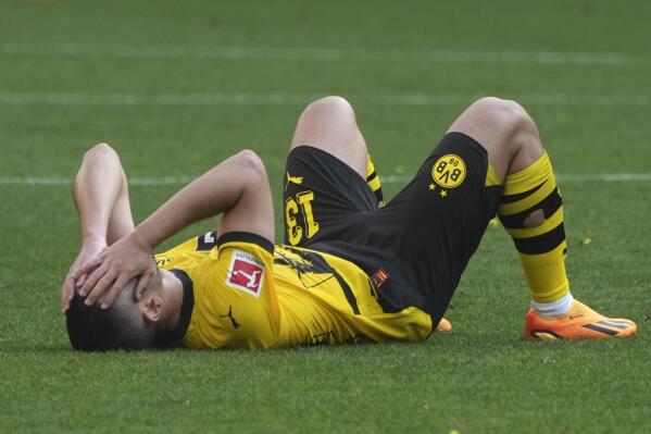 Dortmund's Raphael Guerreiro covers his face after the German Bundesliga soccer match between Borussia Dortmund and FSV Mainz 05 in Dortmund, Germany, Saturday, May 27, 2023. (AP Photo/Michael Probst)