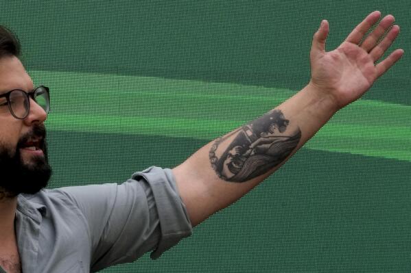 A tattoo of a lighthouse set on the Strait of Magellan decorates the arm of then presidential candidate Gabriel Boric during a rally in Santiago, Chile, Monday, Nov. 1, 2021. The tattoo on the now President-elect´s arm is by Chilean tattoo artist Yumbel Gongora and it shows the famed sea rout in southern Chile where Boric hails from. (AP Photo/Esteban Felix)