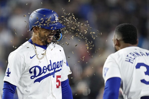 Los Angeles Dodgers' Mookie Betts, left, is showered with a handful of sunflower seeds after hitting a three-run home run in a baseball against the San Diego Padres, in Los Angeles, April 12, 2024. (AP Photo/Mark J. Terrill)