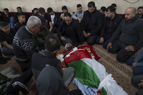 Mourners take the last look at the body of Palestinian Mohammad Shahmawi, 22, at a mosque in the West Bank refugee camp of al-Faraa, Friday, April 12, 2024. Two Palestinians were killed early Friday in confrontations with Israeli forces in the Israeli-occupied West Bank, Palestinian medics and the Israeli military said. The Islamic militant group Hamas said one of those killed was a local commander. (AP Photo/Nasser Nasser)