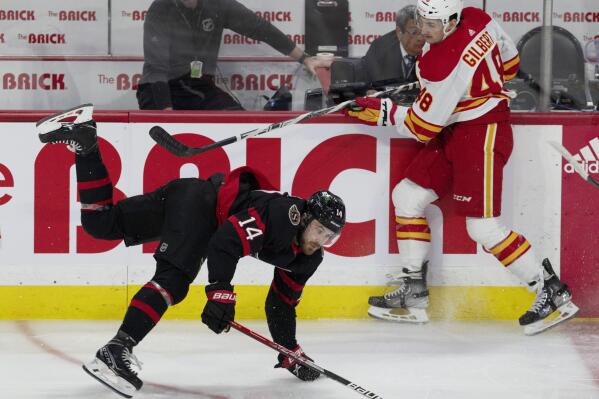 Calgary Flames defenseman Dennis Gilbert gets the upper hand on Ottawa Senators left wing Tyler Motte as they collide along the boards during the first period of an NHL hockey game, Monday, Feb. 13, 2023, in Ottawa, Ontario. (Adrian Wyld/The Canadian Press via AP)