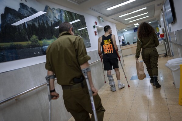Israeli soldiers wounded in the war with Hamas walk in the rehabilitation division of Sheba hospital in Ramat Gan, Israel, Monday, Dec. 18, 2023. (AP Photo/Oded Balilty)