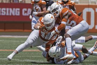 FILE - In this April 24, 2021, file photo, Texas defenders Jake Ehlinger, left, and B.J. Foster, right, tackle Kayvontay Dixon (16) during the first half of the Orange and White spring scrimmage college football game in Austin, Texas. Ehlinger, the younger brother of former Longhorns quarterback Sam Ehlinger, was found dead near campus Thursday, May 6, Austin police said. Officers found the 20-year-old Ehlinger after responding to a call at 12:18 p.m. Police did not detail how they found him but said the death is not considered suspicious. No cause of death was immediately released. (AP Photo/Michael Thomas, File)