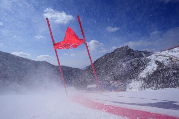 A gate flag bends in the wind after high winds caused the postponement of the start of the mixed team parallel skiing event at the 2022 Winter Olympics, Saturday, Feb. 19, 2022, in the Yanqing district of Beijing. (AP Photo/Robert F. Bukaty)