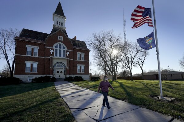 Tisha Coleman, public health administrator for Linn County, walks past the Linn County courthouse in Mound City, Kan., Monday, Dec. 7, 2020. In this community with no hospital, she's failed to persuade her neighbors to wear masks and take precautions against COVID-19, even as cases rise. In return, she's been harassed, sued, vilified and called a Democrat, an insult in her circles. (AP Photo/Charlie Riedel)