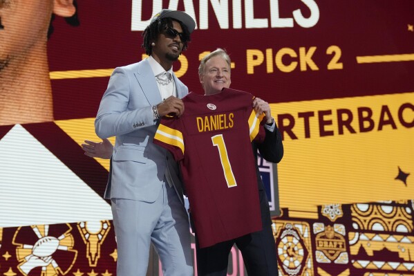 LSU quarterback Jayden Daniels poses with NFL commissioner Roger Goodell after being chosen by the Washington Commanders with the second overall pick during the first round of the NFL football draft, Thursday, April 25, 2024, in Detroit. (AP Photo/Jeff Roberson)