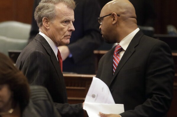 FILE - Illinois Speaker of the House Michael Madigan, D-Chicago, left, speaks with Illinois Rep. Thaddeus Jones, D-Calumet, right, while on the House floor, Nov. 7, 2013, in Springfield Ill. On Monday, Nov. 6, 2023, officials in a suburban Chicago community dropped municipal citations against Hank Sanders, a local news reporter, for what they said were persistent contacts with city officials seeking comment on treacherous fall flooding. Sanders continued to report on the issue, drawing complaints from city officials, including Mayor Thaddeus Jones, who is also a state representative, that he was calling employees to seek comment. (AP Photo/Seth Perlman, File)