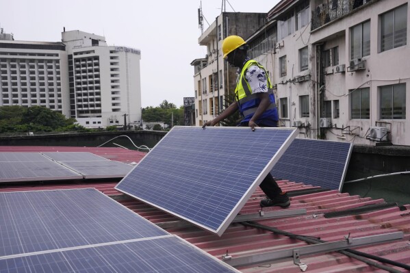 Oladapo Adekunle, an engineer with Rensource Energy, installs solar panels on a roof of a house in Lagos, Nigeria, Thursday, March 21, 2024. Funding for climate tech startups in Africa from the private sector is growing, but there's still a long way to go. (AP Photo/Sunday Alamba)