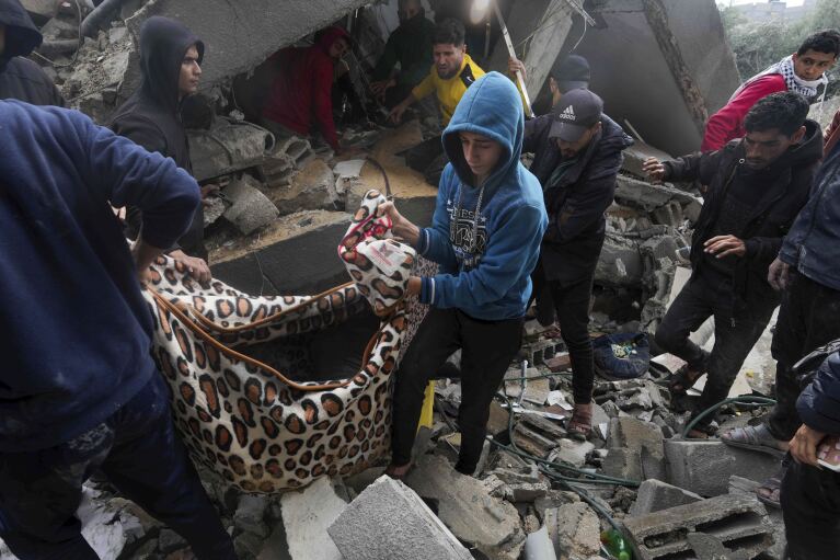 Palestinians carry away a body out of the rubble of the Al Nawasrah family building destroyed in an Israeli airstrike in Maghazi refugee camp, central Gaza Strip, Monday, Dec. 25, 2023. (AP Photo/Adel Hana)