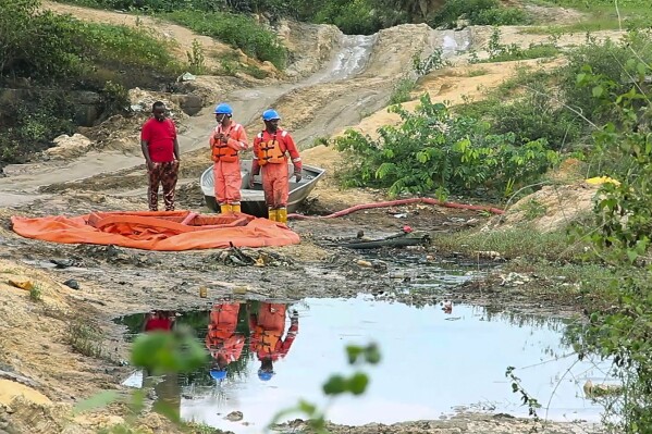 In this grab taken from video, workers stand by a container to collect oil spill waste, in Ogoniland, Nigeria, June 16, 2023. An oil spill at a Shell facility in Nigeria has contaminated farmland and a river. It's upended livelihoods in the fishing and farming communities of part of the Niger Delta, which has long endured environmental pollution caused by the oil industry. (AP Photo)