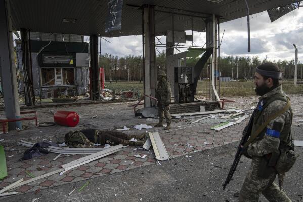 Ukrainian servicemen find a body of their comrade on the destroyed petrol station in the recently recaptured town of Lyman, Ukraine, Monday, Oct. 3, 2022. (AP Photo/Evgeniy Maloletka)