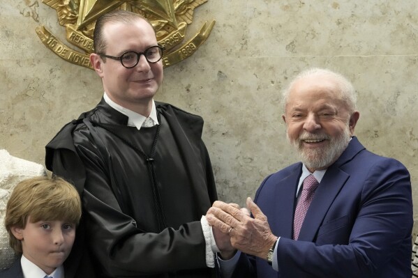 Brazil's President Luiz Inacio Lula da Silva, right, and new Supreme Court Justice Cristiano Zanin, pose for photos after his swearing-in ceremony, in Brasilia, Brazil, Thursday, Aug. 3, 2023. Zanin, a former personal lawyer of Lula, took his seat on Thursday amid criticism that their relationship poses a conflict of interest. (AP Photo/Eraldo Peres)