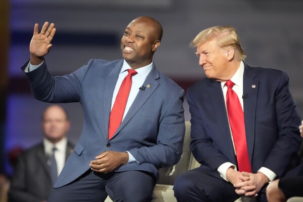 Republican presidential candidate former President Donald Trump looks to Sen. Tim Scott, R-S.C., during a Fox News Channel town hall Tuesday, Feb. 20, 2024, in Greenville, S.C. (AP Photo/Chris Carlson)