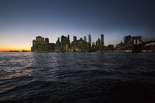 
              The sun sets behind the New York skyline and the Brooklyn Bridge, right, on Oct. 19, 2017.  Five years after Superstorm Sandy was supposed to have taught the country a lesson about the dangers of living on an undefended coast, there's still no city in America that's truly prepared for the challenges of climate change and the storms it will deliver. (AP Photo/Mark Lennihan)
            