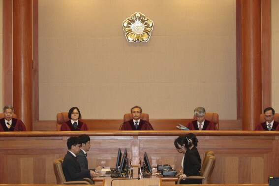South Korea's Constitutional Court Chief Justice Yoo Nam-seok, top center, and other judges sit before the judgment at the Constitutional Court in Seoul, South Korea, Tuesday, July 25, 2023. South Korea's Constitutional Court on Tuesday overturned the impeachment of the public safety minister ousted over a Halloween crowd surge that killed nearly 160 people last October at a nightlife district in the capital, Seoul. (Yonhap via AP)