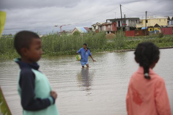 A man wades through flood water on his way to a shop in Antananarivo, Madagascar, Monday, Jan. 24, 2022. Tropical storm Ana has caused widespread flooding in Madagascar, including in the capital city, causing the deaths of 34 people and displacing more than 55,000, officials said Monday. (AP Photo/Alexander Joe)
