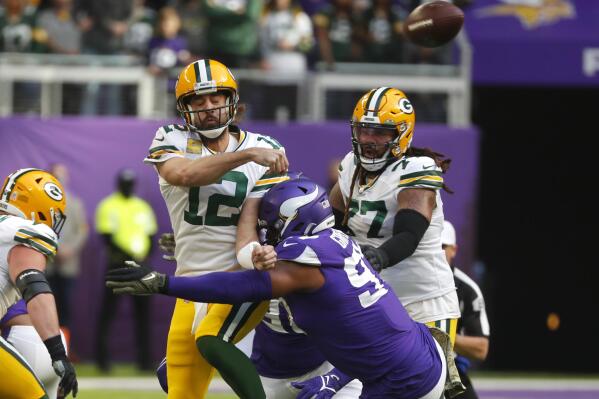 Green Bay Packers quarterback Aaron Rodgers (12) passes as he is hit by Minnesota Vikings defensive end Everson Griffen (97) during the first half of an NFL football game, Sunday, Nov. 21, 2021, in Minneapolis. (AP Photo/Bruce Kluckhohn)