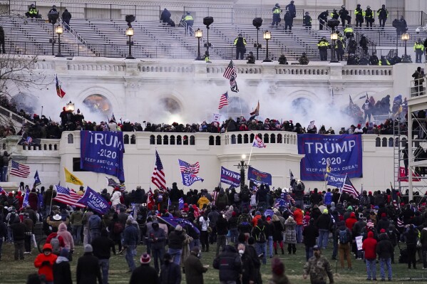 FILE - Violent insurrectionists loyal to President Donald Trump storm the U.S. Capitol, Jan. 6, 2021, in Washington. An Arkansas truck driver who beat a police officer with a flagpole attached to an American flag during the U.S. Capitol riot was sentenced Monday, July 24, 2023, to more than four years in prison. Peter Francis Stager struck the Metropolitan Police Department officer with his flagpole at least three times as other rioters pulled the officer, head first, into the crowd outside the Capitol on Jan. 6, 2021. The bruised officer was among more than 100 police officers injured during the riot. (AP Photo/John Minchillo, File)