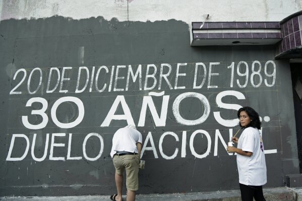 In this Dec. 15, 2019 photo, activists paint a the Spanish message: "Dec. 20, 1989. 30 years. National Day of Mourning," ahead of the 30th anniversary of U.S. invasion of Panama in the El Chorrillo neighborhood where former Gen. Manuel A. Noriega operated his headquarters and is an area that was bombed during the invasion in Panama City. This week relatives won a victory when the government declared Friday, Dec. 20, 2019 a day of national mourning for the first time. (AP Photo/Arnulfo Franco)